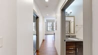 Located at 8 E Long St in the heart of downtown Columbus, Ohio, this one-bedroom, two-bathroom unit offers a well-designed single-floor layout with thoughtful finishes throughout. The kitchen serves as a central highlight, featuring rich dark wood cabinetry, granite countertops, and a peninsula with a built-in sink — ideal for both cooking and casual dining. Black appliances, including a refrigerator with ice maker and an electric range, are complemented by stylish pendant lighting and a track lighting system overhead, all set above warm hardwood flooring. The open layout allows natural light to flow from the living area, which boasts large windows offering views of the surrounding downtown streetscape. The bedroom provides a comfortable retreat with plush carpeting, generous wall space, a dedicated closet, and access to the adjacent carpeted area. The bathroom is clean and functional, finished with marble-style tile flooring, a granite-topped vanity with dark wood cabinetry, and a full tub/shower combination. A second bathroom adds convenience to the overall layout. With its downtown location, modern interior finishes, and efficient use of space, this unit is well-suited for those seeking urban living in Columbus.
