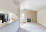 Located at 3001 Hahn Dr in Modesto, California, this single-story, one-bedroom, one-bathroom residence offers a well-organized layout across a compact yet functional floor plan. The living room immediately impresses with dramatic vaulted ceilings that lend an open, airy feel well beyond what the footprint might suggest. A classic fireplace with a glass-paneled screen serves as the room's focal point, flanked by neutral-toned walls and plush carpeting that extends throughout the living and sleeping areas. Natural light filters in through windows, enhancing the bright, clean aesthetic. The kitchen is designed in a galley style, featuring crisp white cabinetry, light stone-toned countertops, and black appliances including a range, microwave, refrigerator, and dishwasher. A pass-through counter connects the kitchen to the living area, promoting an open feel. Light hardwood-style flooring runs through the kitchen and entrance areas. The bedroom is a comfortably sized retreat with soft carpet, a window providing natural light, and access to a generously proportioned walk-in closet outfitted with wrap-around hanging rods and shelving. The bathroom includes a full-size soaking tub and shower combo with a clean white surround and built-in shelving niches for added convenience.