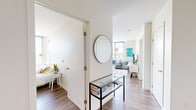 Located on the seventh floor at 199 N Harvard Street in Boston's Allston neighborhood, this well-appointed 2-bedroom, 2-bathroom apartment offers a bright and contemporary living experience. Hardwood floors flow throughout the open-concept layout, connecting the kitchen, living room, and hallway seamlessly.

The kitchen is a standout feature, showcasing high-gloss dark wood cabinetry, white quartz countertops, a subway tile backsplash, and a full suite of stainless steel appliances. A peninsula with seating overlooks the living area, which is bathed in natural light through expansive floor-to-ceiling windows offering sweeping city and treetop views.

The welcoming entryway hallway leads to both bedrooms. The primary bedroom is generously sized, featuring large windows with open views and ample natural light. The second bedroom also benefits from oversized windows and includes built-in wall shelving with an integrated desk. Both rooms are finished with rich hardwood flooring.

The two bathrooms are clean and modern in design. One features a frameless glass walk-in shower with white subway tile, while the second offers a shower-tub combination. Both include white vanities with undermount sinks and tile flooring.