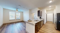 Located at 2425 Premier Dr in Plano, TX, this single-story 2-bedroom, 3-bathroom unit offers a well-organized layout with consistent design finishes throughout. Wood-style plank flooring runs through the living areas, bedrooms, and bathrooms, providing a cohesive aesthetic across the entire floor plan.

The kitchen is a standout feature, designed in a galley style with dark espresso cabinetry, granite countertops, stainless steel appliances including a refrigerator, microwave, and range, and a peninsula with an undermount sink. Recessed lighting enhances the workspace and connects visually to the adjacent living area.

Both bedrooms are modestly sized, each receiving natural light through windows fitted with horizontal blinds. Ceiling fans are present in the bedrooms, supporting comfort and ventilation. The primary bedroom offers a cozy footprint with direct access to hallway areas.

The three bathrooms maintain a uniform finish palette, featuring granite-topped dark vanities, wood-style flooring, white tiled tub-shower combinations, and chrome fixtures. A dedicated utility room and a closet add practical storage capacity. Neutral wall tones throughout create a clean, move-in-ready environment suited for efficient everyday living.