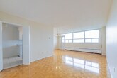 Located at 601 Finch Avenue West in North York, Toronto, this well-appointed one-bedroom, one-bathroom unit offers a practical and comfortable layout. The living room is a standout space, characterized by gleaming parquet flooring throughout and a wall of large floor-to-ceiling windows that flood the room with natural light while framing sweeping views of the Toronto skyline and surrounding greenery. A classic chandelier adds a touch of elegance to the open living and dining area. The bedroom is generously sized, featuring the same warm parquet flooring, a large window with scenic outdoor views, a baseboard heating unit, and a built-in double closet providing ample storage. The kitchen is finished with white cabinetry, marble-patterned countertops, and clean ceramic tile flooring, offering a bright and functional cooking space. The bathroom includes a full soaker tub with a handheld showerhead and is finished with neutral cream tiles accented by a decorative tile border, creating a clean and timeless aesthetic. A hallway connects all rooms efficiently. The unit is bathed in natural light throughout, with baseboard heating ensuring year-round comfort.