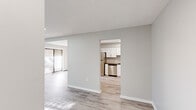 Located at 65 Avonwood Rd in Avon, CT, this well-appointed 2-bedroom, 2-bathroom single-floor residence offers a clean, modern aesthetic with a cohesive neutral color palette carried throughout every room. Light wood-style flooring runs through the main living areas, creating a bright and airy feel that connects the open living room, entrance, and hallway seamlessly. The living room is generously proportioned, featuring recessed lighting and a wall-mounted HVAC unit, and opens toward the kitchen through a defined archway. The kitchen is a standout space, outfitted with crisp white shaker cabinets, subway tile backsplash, stainless steel appliances including a range and dishwasher, and durable countertops — all illuminated by recessed overhead lighting. Both bedrooms are comfortably sized, featuring plush wall-to-wall carpeting, natural light from windows with blinds, and baseboard heating. The spacious primary bedroom includes a large walk-in closet with dual shelving rods and carpeted flooring for added comfort. Both bathrooms are finished with large-format tile flooring, modern vanities, round mirrors, and chrome fixtures. The layout flows efficiently through a central hallway connecting all rooms, offering a practical and cohesive living experience.