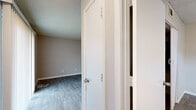 This single-floor, 3-bedroom, 2-bathroom residence offers a practical and comfortable layout designed to maximize everyday living. The open-concept living room is bright and inviting, featuring durable wood-look laminate flooring, neutral gray walls, a textured ceiling, and a sliding glass door that floods the space with natural light and provides outdoor access. The adjacent galley-style kitchen is efficiently laid out with white cabinetry, speckled countertops, black appliances including a refrigerator, electric range, and dishwasher, complemented by a stainless steel sink. Three bedrooms provide versatile accommodations; the primary bedroom is generously sized and features plush carpet, a ceiling fan with light fixture, a window for natural light, and a closet with bifold doors. The additional bedrooms are carpeted with neutral tones and windows that bring in daylight. Two full bathrooms each include a tub/shower combination and clean white finishes. One bathroom features wood-look flooring and a vanity with speckled countertop. Hallways and a dedicated closet add to the storage and circulation options throughout. The consistent use of neutral tones and durable finishes throughout the space creates a cohesive and move-in-ready environment.