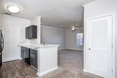 Located at 101 Walden Landing Dr in Hampton, Georgia, this single-story residence offers a well-designed, open-concept floor plan that maximizes both functionality and comfort. The living area is generously proportioned, featuring plush wall-to-wall carpeting, crown molding, and a ceiling fan that adds a classic finishing touch. A glass-paneled door floods the space with natural light, creating a bright and welcoming atmosphere. Crown molding continues throughout, lending an air of elegance to the interiors.

The kitchen is a standout feature, showcasing a galley-style layout with dark-toned cabinetry, sleek white countertops, and durable hardwood-style flooring. Black appliances — including a refrigerator, range, microwave, and dishwasher — are neatly integrated into the design. A pass-through counter connects the kitchen to the dining and living areas, promoting an open and social flow throughout the home.

The bathroom is thoughtfully appointed with hardwood-style flooring, a combination soaking tub and shower, a single vanity with cabinet storage, and a large mirror with overhead lighting. The layout is efficient and practical, making excellent use of the available space. Overall, this residence delivers a cohesive, move-in-ready environment with quality finishes throughout.