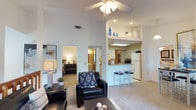This single-floor, 3-bedroom, 3-bathroom residence offers a generous and thoughtfully designed layout that balances comfort and functionality. The open-concept living area immediately impresses with soaring vaulted ceilings and a ceiling fan overhead, creating an airy and expansive atmosphere. Soft carpeting throughout the main living space adds warmth, while recessed lighting and a skylight in the kitchen area ensure the home feels bright and welcoming.

The kitchen features white cabinetry, a full-size refrigerator, and a raised breakfast bar with seating for multiple stools, making it ideal for casual dining and entertaining. The bar-height counter connects the kitchen to the main living area seamlessly, enhancing the open feel of the floor plan.

The bedrooms are accessible directly from the main living space and are well-appointed, with ample room for furnishings. The three full bathrooms provide convenience and privacy for residents and guests alike. Elevated display shelving near the kitchen adds an architectural detail that contributes to the home's character.

Overall, this residence delivers a bright, open, and comfortable living environment with practical design elements and generous proportions throughout every room.