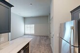 Located on Virginia Avenue in Culver City, California, this one-bedroom, one-bathroom unit offers a thoughtfully designed layout that maximizes every square foot of its compact footprint. The open-concept living and kitchen area features warm hardwood-style flooring, transitioning seamlessly into the carpeted living space. The kitchen is a standout, outfitted with sleek slate-blue cabinetry, quartz countertops, a stainless steel single-basin sink with a matte black faucet, and a stainless steel range — delivering a modern, contemporary aesthetic. The generously proportioned bedroom is carpeted and bathed in natural light through a window dressed with horizontal blinds. It features neutral, light-toned walls and direct access to a dedicated walk-in closet equipped with built-in shelving and hanging rods, offering ample storage. The bathroom is clean and functional, showcasing a combination tub and shower with a curved curtain rod, brushed nickel fixtures, a blue vanity with an integrated sink, and wood-look flooring. The overall design palette — soft grays, whites, and muted blues — lends the space a calm, contemporary feel well-suited to modern living in the heart of Culver City.