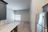 Located on Virginia Avenue in Culver City, California, this one-bedroom, one-bathroom unit offers a thoughtfully designed layout that maximizes every square foot of its compact footprint. The open-concept living and kitchen area features warm hardwood-style flooring, transitioning seamlessly into the carpeted living space. The kitchen is a standout, outfitted with sleek slate-blue cabinetry, quartz countertops, a stainless steel single-basin sink with a matte black faucet, and a stainless steel range — delivering a modern, contemporary aesthetic. The generously proportioned bedroom is carpeted and bathed in natural light through a window dressed with horizontal blinds. It features neutral, light-toned walls and direct access to a dedicated walk-in closet equipped with built-in shelving and hanging rods, offering ample storage. The bathroom is clean and functional, showcasing a combination tub and shower with a curved curtain rod, brushed nickel fixtures, a blue vanity with an integrated sink, and wood-look flooring. The overall design palette — soft grays, whites, and muted blues — lends the space a calm, contemporary feel well-suited to modern living in the heart of Culver City.