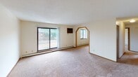 This single-floor unit offers a practical, well-organized layout with distinct living, sleeping, and functional zones. The living area is generously sized, featuring neutral-toned carpet, a textured ceiling, and a sliding glass door that opens to a balcony, bringing in natural light and outdoor views. A charming arched pass-through window adds an architectural accent between spaces.

The bedrooms are comfortably proportioned, each equipped with ceiling fans, baseboard heating, and windows that provide natural light and outdoor views. Neutral carpet and light-colored walls create a clean, understated aesthetic throughout the sleeping areas.

The kitchen is designed for efficiency, featuring warm oak cabinetry both above and below the countertops, a double-basin stainless steel sink, a white electric range, and a dishwasher. Light tile flooring extends through the kitchen and connects to adjacent areas.

The bathroom includes tile flooring, a full tub and shower combination, a toilet, and a single-sink vanity with an oak cabinet base, light countertop, and a framed mirror with overhead lighting. Textured ceilings are consistent throughout the unit, and baseboard heating is present in multiple rooms.