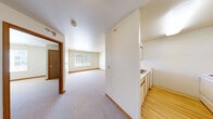 This 2-bedroom, 1-bathroom single-floor unit offers a straightforward and functional layout designed for comfortable everyday living. The open living area is carpeted and filled with natural light, highlighted by a sliding glass door that opens to an outdoor view of green lawns and surrounding buildings. The kitchen is efficiently laid out with light wood-toned laminate flooring, white cabinetry, a refrigerator, and a range, seamlessly connected to the living space via a partial dividing wall. Two hallways guide residents through the unit, providing easy access to all areas including two closets and a dedicated laundry space. The primary bedroom is a well-proportioned room with plush carpeting and its own closet, while the second bedroom features a window that brings in natural daylight. The bathroom is clean and utilitarian, featuring a walk-in shower stall equipped with grab bars for added accessibility, set on neutral tile flooring. Throughout the unit, warm wood-toned baseboards and door frames provide a consistent finishing detail. The overall palette of soft whites and neutral tones creates a calm, move-in-ready atmosphere well-suited for a variety of living arrangements.