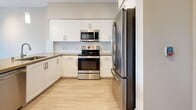 Located at 770 S Harbor Blvd in Fullerton, California, this thoughtfully designed two-story residence offers a well-organized layout across two floors. The main level features a bright, open-concept kitchen and dining area with white shaker cabinetry, stainless steel appliances including a refrigerator, range, and built-in microwave, a peninsula with pendant lighting and a neutral quartz-style countertop, and light hardwood-style flooring throughout. The spacious living room flows naturally from the kitchen and opens to one of two private balconies, filling the space with natural light and outdoor views. An additional room serves as a versatile workshop, adding functional flexibility to the layout. The upper level hosts the carpeted bedroom, complete with a ceiling fan, a large window with outdoor views, and a built-in closet. Two full bathrooms serve the residence — one featuring accessibility-friendly grab bars and large-format tile flooring, and the other offering a full soaking tub with shower. Five closets provide ample storage throughout. The clean, neutral color palette, recessed lighting, and modern finishes lend the space a fresh, contemporary ambiance suitable for a variety of lifestyles.