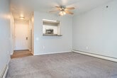 Located at 902 N High Point Rd in Madison, WI, this one-bedroom, one-bathroom unit offers a well-organized single-floor layout designed for comfortable everyday living. The kitchen is a functional galley-style space outfitted with white cabinetry, gray laminate countertops, a stainless steel double-basin sink with a pull-down faucet, and stainless steel appliances including a range, microwave, and dishwasher. Wood-look vinyl plank flooring runs throughout the kitchen and extends toward the bathroom. A pass-through opening connects the kitchen to the combined living area, which is carpeted and brightened by a ceiling fan with light fixture. The living room opens directly to a private balcony via a sliding glass door, allowing natural light to fill the space and providing outdoor views of the surrounding residential community. The bedroom is a well-proportioned, carpeted room featuring a window with blinds, baseboard heating, and access to a dedicated walk-in closet. The bathroom is finished with wood-look vinyl plank flooring, a white vanity with storage, a large mirror with overhead lighting, and a full bathtub and shower combination with grab bars. Clean, neutral tones and practical finishes give the unit a cohesive and move-in ready character throughout.