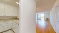 Located at 300 S Gramercy Pl in the heart of Los Angeles, this one-bedroom, two-bathroom residence offers a thoughtfully arranged single-floor layout. Warm-toned hardwood floors extend throughout the main living areas, lending a clean, cohesive feel to the space. The open living room is generously proportioned, filled with natural light from large windows, and features a ceiling fan overhead. A textured ceiling adds character throughout.

The kitchen connects seamlessly to the living area via a pass-through counter, and is equipped with white cabinetry, granite-style countertops, a full suite of white appliances including a refrigerator, range, and built-in microwave, along with a decorative tile backsplash.

The spacious primary bedroom continues the hardwood flooring and includes a wall-mounted air conditioning unit and a window with outdoor views. Both bathrooms are well-appointed — one features stone-tiled walls with a soaking tub and frosted glass sliding shower door, while the other offers a white vanity with under-cabinet storage and a large mirror. Together, they provide practical convenience and a polished aesthetic suited for comfortable city living.