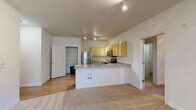 This 2-bedroom, 2-bathroom single-story residence offers a thoughtfully designed layout that maximizes comfort and functionality. The open-concept kitchen and living area serves as the heart of the home, featuring light wood cabinetry with ample storage, stainless steel appliances including a refrigerator, range, and microwave, and a peninsula with a built-in sink that flows seamlessly into the carpeted living area. Track lighting illuminates the space overhead. Hardwood-style flooring runs throughout the kitchen and hallways, while plush carpet adds warmth to the living and bedroom areas. A dedicated hallway connects the bedrooms and bathrooms, with access to a generous walk-in closet outfitted with wire shelving. The primary bedroom is spacious, featuring a ceiling fan with light fixture and a large window that invites natural light and outdoor views. The second bedroom also includes a ceiling fan. Both bathrooms are finished with warm wood vanities, countertop sinks, mirrors with vanity lighting, and tub/shower combinations. A dedicated laundry area houses a full-size side-by-side washer and dryer with overhead wire shelving. The kitchen also benefits from a separate pantry closet with built-in wire shelving, providing excellent additional storage.
