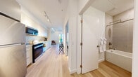 Located at 3271 Hilltown Dr in Kelowna, BC, this thoughtfully designed one-bedroom, one-bathroom unit offers a clean, modern aesthetic throughout its efficiently arranged single-floor layout. Light hardwood flooring flows seamlessly across every room, complementing the crisp white walls and creating a bright, cohesive atmosphere.

The open-concept kitchen and living area forms the heart of the unit. The kitchen is well-appointed with full-height white cabinetry, a textured tile backsplash, white quartz countertops, a double stainless steel sink, and a complete suite of stainless steel appliances including a refrigerator, range, over-the-range microwave, and dishwasher. Adjacent to the kitchen, the living area provides a comfortable and functional space with a large interior window that looks directly into the bedroom, enhancing the sense of openness.

The bedroom is a serene retreat featuring a sliding closet door and a window overlooking the private balcony, where mountain and outdoor scenery can be enjoyed. The four-panel white-framed window brings in generous natural light.

The bathroom is finished with large-format neutral tiles surrounding a full soaker tub and shower combination, a white vanity with quartz countertop, and light hardwood-style flooring, maintaining the unit's clean and contemporary character throughout.