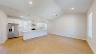 Located in Frisco, TX, this single-story, 3-bedroom, 2-bathroom home offers a well-designed layout that balances comfort and functionality. The open-concept kitchen and living area serves as the heart of the home, featuring vaulted ceilings with recessed lighting, light hardwood-style flooring, and an abundance of natural light. The kitchen is equipped with white shaker cabinetry, white countertops, a subway tile backsplash, stainless steel appliances including a side-by-side refrigerator and a wall-mounted range hood, and a central island that flows seamlessly into the living space. The generously sized primary bedroom includes plush carpeting, a ceiling fan, and a walk-in closet with built-in shelving and hanging rods. The additional bedrooms also feature carpet flooring, ceiling fans, and windows that invite natural light. The primary bathroom offers a clean, modern aesthetic with a double-sink vanity, wood-look flooring, and a glass-enclosed walk-in shower. A dedicated laundry room houses a full-size washer and dryer. The attached two-car garage provides ample storage and parking. Outside, the painted brick exterior is complemented by a fenced backyard with a central HVAC unit.
