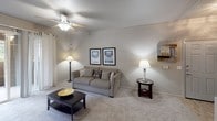 This single-floor residence offers a thoughtfully designed layout that balances comfort and functionality across its key living spaces. The living room serves as the heart of the home, featuring plush carpeting, crown molding, and a ceiling fan overhead. Neutral-toned walls create a calm, versatile backdrop, while a sliding glass door opens to a private outdoor balcony, allowing natural light to fill the space and providing a pleasant outdoor retreat. The galley-style kitchen is equipped with warm wood cabinetry extending to the ceiling for ample storage, white appliances including a refrigerator and range, a granite-look countertop, and light wood-style flooring that adds a clean, modern touch. A dedicated dining nook sits adjacent to the kitchen, defined by a pendant light fixture and a decorative wall mirror, with convenient in-unit washer and dryer hookups just steps away. The bedroom is a peaceful retreat with soft carpeting, a ceiling fan, natural light from a curtained window, and access to a walk-in closet with built-in shelving. The bathroom is clean and bright, featuring light wood-style flooring, a single vanity with warm wood cabinetry, a large mirror, and a shower-tub combination. Throughout the unit, consistent neutral finishes and thoughtful details create a cohesive and inviting living environment.