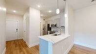 This well-appointed 2-bedroom, 2-bathroom residence offers a thoughtfully designed single-level layout that balances comfort and functionality. The open-concept kitchen and living area serves as the heart of the home, featuring light wood-style flooring, recessed lighting, and a striking peninsula island topped with a veined marble-look quartz countertop. The kitchen is outfitted with stainless steel appliances, white shaker cabinetry, a tile backsplash, and pendant lighting that adds a modern touch. The peninsula opens seamlessly toward the living area, creating an ideal space for both everyday living and entertaining.

Both bedrooms are carpeted and filled with natural light from large windows fitted with horizontal blinds. Ceiling fans provide year-round comfort, and each room offers a calm, neutral palette. The primary bedroom includes a dedicated walk-in closet with built-in shelving and hanging rods for organized storage. A second bedroom features built-in wall shelving, adding versatile functionality.

The bathrooms are clean and well-finished, with one featuring a full soaking tub and shower combination, tiled surround, a grey vanity with a white countertop, and a mirrored medicine cabinet. An in-unit laundry area with a full-size washer and dryer adds everyday convenience, completing this practical and welcoming home.