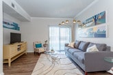 This single-floor residence offers a thoughtfully designed layout that balances style and functionality throughout. The living room serves as the heart of the home, featuring crown molding, wood-look flooring, and a striking teal-painted ceiling that adds a bold design accent. A large sliding glass door floods the space with natural light and provides outdoor access, while a statement arc floor lamp and vibrant wall art contribute to the room's modern, inviting character.

Adjacent to the living area, the dining space is defined by its intimate scale and direct connection to the kitchen, making it ideal for everyday meals and entertaining. The kitchen is outfitted with dark cabinetry, a subway tile backsplash, stainless steel appliances, and a light-toned countertop breakfast bar that opens to the dining area.

The bedrooms are carpeted and comfortably sized, each featuring ceiling fans and ample natural light. At least one bedroom includes a walk-in closet, providing generous storage. The bathroom features dark wood cabinetry, a wide vanity with a single sink, and wood-look flooring that ties into the home's overall aesthetic.

A dedicated in-unit laundry room with a full-size washer and dryer adds everyday convenience. Throughout, the space maintains a cohesive, contemporary design with warm tones and practical finishes.