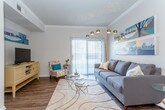 This single-floor residence offers a thoughtfully designed layout that balances style and functionality throughout. The living room serves as the heart of the home, featuring crown molding, wood-look flooring, and a striking teal-painted ceiling that adds a bold design accent. A large sliding glass door floods the space with natural light and provides outdoor access, while a statement arc floor lamp and vibrant wall art contribute to the room's modern, inviting character.

Adjacent to the living area, the dining space is defined by its intimate scale and direct connection to the kitchen, making it ideal for everyday meals and entertaining. The kitchen is outfitted with dark cabinetry, a subway tile backsplash, stainless steel appliances, and a light-toned countertop breakfast bar that opens to the dining area.

The bedrooms are carpeted and comfortably sized, each featuring ceiling fans and ample natural light. At least one bedroom includes a walk-in closet, providing generous storage. The bathroom features dark wood cabinetry, a wide vanity with a single sink, and wood-look flooring that ties into the home's overall aesthetic.

A dedicated in-unit laundry room with a full-size washer and dryer adds everyday convenience. Throughout, the space maintains a cohesive, contemporary design with warm tones and practical finishes.