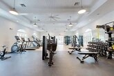 Located at 25 Silver Moon Circle in St. Augustine, FL, this fitness center offers a comprehensive, single-floor layout spanning a generously sized footprint designed to accommodate a wide range of workout needs. The facility is divided into distinct zones, each purpose-built for specific training disciplines.

The main gym floor features an extensive selection of Matrix strength machines, free weights, benches, and a full dumbbell rack, alongside cardio equipment including treadmills, ellipticals, stair climbers, and rowing machines. The space is finished with durable rubber flooring and light hardwood in the cardio area, complemented by coffered ceilings, large ceiling fans, and pendant lighting that create a bright, airy atmosphere. Arched windows throughout allow abundant natural light to fill the space.

A dedicated cycling studio accommodates multiple stationary bikes arranged in rows, finished with plush carpet flooring, a tray ceiling with warm ambient uplighting, wall-mounted sconces, and expansive arched windows overlooking the outdoors — creating an energizing yet refined environment.

A separate multipurpose studio provides an open, flexible space ideal for group fitness, yoga, or functional training, outfitted with carpeted flooring, a tray ceiling, natural light from multiple arched windows, and wall-mounted accessories. The overall design balances a clean, upscale aesthetic with practical, high-performance fitness functionality.