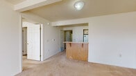 Located at 1214 Farm Crest Cir in Mishawaka, Indiana, this single-floor residence offers a practical and straightforward layout designed for comfortable everyday living. The living area is generously sized, featuring neutral-toned carpeting that extends throughout the main spaces and a set of glass doors that invite natural light and provide outdoor views. A structural beam accent frames the transition between the living area and the kitchen pass-through, which features a wooden breakfast bar with warm oak tones. The kitchen is visible beyond the bar and includes a refrigerator and range, with additional storage and workspace along the cabinetry.

The bedrooms are carpeted and well-lit, each benefiting from windows fitted with blinds that allow for adjustable natural light. Closet access is provided in the bedrooms, contributing to overall storage. Two bathrooms serve the unit; one includes a walk-in shower stall with grab bar and a vanity with under-sink cabinetry, while the second offers a full bathtub and shower combination, also with grab bars and a similarly styled vanity. Both bathrooms feature earthy tile flooring. A dedicated laundry room accommodates a full-sized washer and dryer with additional wire shelving overhead, adding functional utility to the home.