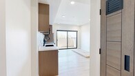 Located at 1047 Fedora St, Unit 506 in Los Angeles, this modern 2-bedroom, 2-bathroom residence offers a thoughtfully designed layout with contemporary finishes throughout. Light wood-tone flooring runs continuously across the unit, complementing the clean white walls and recessed lighting that give the space a bright, cohesive feel.

The open kitchen is outfitted with warm wood cabinetry, white countertops, and a full suite of stainless steel appliances including a refrigerator, electric range, microwave, and dishwasher. The kitchen flows seamlessly into the adjacent living area, making it well-suited for everyday functionality.

The primary bedroom features dual closets with stylish paneled wood doors and a window that brings in natural light. The second bedroom also includes a closet with matching paneled doors and its own window. Both rooms share the same light hardwood flooring and neutral palette.

The two bathrooms are finished in a modern style. One features a floating wood-tone vanity with a white basin, a framed rectangular mirror, mosaic tile flooring, and a window. The second bathroom includes a walk-in shower adorned with herringbone white tile, a matching floating vanity, and a sleek black-framed mirror. Three hallways connect the rooms efficiently throughout the unit.