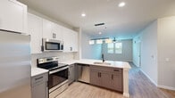 Located at Integra Town Center in Daytona Beach, FL, this well-appointed one-bedroom, one-bathroom residence offers a thoughtfully designed single-floor layout. The open-concept kitchen serves as the heart of the home, showcasing two-tone cabinetry with crisp white upper cabinets and warm gray lower cabinets, quartz countertops, stainless steel appliances, and a peninsula island with an undermount sink and matte black faucet. A trio of pendant lights illuminates the island, creating a stylish focal point that flows seamlessly into the living area. Durable wood-look plank flooring extends throughout the entire space, adding warmth and continuity. The living area is bright and airy, benefiting from natural light admitted through windows and complemented by a ceiling fan. The primary bedroom is a comfortable retreat with dual windows, a ceiling fan, and a dedicated closet for storage. The bathroom is finished in a modern aesthetic, featuring a dark-framed glass-enclosed shower, a sleek vanity with a white countertop, a large mirror, and matte black hardware accents. Clean neutral walls and recessed lighting throughout the home create a fresh, contemporary ambiance ideal for comfortable living.