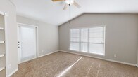 This single-floor home offers a thoughtfully designed layout that balances comfort and functionality. The kitchen serves as a standout feature, showcasing crisp white cabinetry, granite countertops, and a full suite of stainless steel appliances including a range, over-the-range microwave, refrigerator, and dishwasher. A subway tile backsplash in soft gray tones adds a modern touch, while warm hardwood-style flooring grounds the space with an inviting feel. A peninsula with an integrated sink provides additional prep space and a natural transition into the adjoining living areas.

The bedrooms are generously proportioned, each featuring plush carpet flooring, neutral gray walls, and ceiling fans for year-round comfort. The primary bedroom is particularly noteworthy, boasting vaulted ceilings that lend an airy, elevated quality to the room, along with large windows fitted with horizontal blinds that allow natural light to filter in softly. A walk-in closet with built-in shelving adds practical storage. Additional bedrooms mirror the clean, neutral aesthetic with standard ceiling heights and ample natural light. Throughout the home, white trim and doors provide a crisp, cohesive finish that complements the understated color palette.