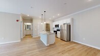 This thoughtfully laid-out 2-bedroom, 1-bathroom residence offers a efficient and functional single-floor plan. The open-concept kitchen and living area serves as the heart of the home, anchored by a central kitchen island with a granite countertop and integrated sink, illuminated by stylish pendant lighting. The kitchen is equipped with stainless steel appliances, including a refrigerator, range, and microwave, complemented by white shaker-style cabinetry, a subway tile backsplash, and recessed lighting throughout. Crown molding adds a refined architectural detail to the space. Light hardwood flooring flows seamlessly through the main living areas, enhancing the bright, airy atmosphere. The living room features a ceiling fan, crown molding, and sliding glass doors that open to a private balcony, inviting natural light and outdoor views. The bedrooms offer plush carpeting and panel-style doors, providing a comfortable retreat. The bathroom is appointed with a granite-topped vanity with shaker cabinetry, a full tub-shower combination, and hardwood-style flooring. A dedicated laundry area with wire shelving and washer/dryer hookups adds everyday convenience to this well-appointed home.