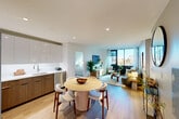 Located on the third floor of North Tower in Jamaica, NY, this well-appointed 2-bedroom, 2-bathroom residence offers a thoughtfully designed open-concept layout bathed in natural light. Light hardwood floors run throughout, complementing the clean, contemporary aesthetic.

The kitchen and dining area flow seamlessly together, featuring two-tone cabinetry with glossy white uppers and warm wood lower cabinets, white quartz countertops, stainless steel appliances including a gas range, built-in microwave, and dishwasher. A round dining table sits just steps away, making the space ideal for entertaining.

The living room opens to expansive floor-to-ceiling windows that frame outdoor views and fill the space with natural light. The primary bedroom is generously sized with large windows offering city views, while the second bedroom also benefits from ample natural light through its own set of windows.

Two bathrooms serve the unit: one features a full soaking tub with overhead shower and clean white tile surround, and the second is a sleek, modern full bath with large-format grey floor tiles and a white floating vanity. Additional features include three closets, an in-unit laundry area, and a smart home panel. The overall ambiance is bright, modern, and inviting.