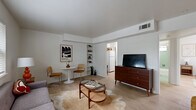 Located at 5203 Gaston Avenue in Dallas's 75214 zip code, this single-floor, one-bedroom, one-bathroom unit offers a well-organized layout across a compact but thoughtfully designed footprint. Light wood flooring runs throughout, lending a clean, cohesive aesthetic to every room.

The living room serves as the heart of the unit, featuring a natural window that draws in ample daylight and a built-in bookshelf that adds both storage and character. The space comfortably accommodates a sofa, coffee table, and a small dining area, reflecting a practical mid-century modern sensibility.

The kitchen is efficiently laid out with white appliances, including a full-size refrigerator and range, complemented by an adjacent pantry that provides extra storage. A hallway connects the main living areas to the private bedroom, which features a window with outdoor views, light-filled walls, a closet, and enough room for a queen-sized bed with nightstands.

The bathroom retains a charming retro character, highlighted by classic sage-green ceramic tile lining the tub and shower surround with chrome fixtures. Every room in this unit is clean, well-maintained, and designed to maximize function within its modest scale, making it a practical and characterful home in Dallas.
