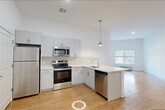 Located at 115 Main Street in Lincoln Park, NJ, this well-appointed one-bedroom, one-bathroom unit offers a clean, modern design throughout its single-floor layout. The open-concept kitchen and living area serves as the heart of the home, featuring light hardwood flooring, crisp white walls, and generous ceiling height that enhances the sense of spaciousness. The kitchen is outfitted with stainless steel appliances — including a refrigerator, electric range, built-in microwave, and dishwasher — complemented by sleek gray cabinetry, a white quartz peninsula countertop, a hexagonal tile backsplash, and a pendant light fixture. Natural light flows in through windows fitted with blinds, brightening both the living and bedroom areas. The bedroom is a comfortable, well-proportioned room with hardwood floors, a window overlooking the exterior, and access to a walk-in closet with wire shelving. A second closet with louvered doors provides additional storage near the kitchen. The bathroom features white tile flooring, a clean white vanity, and accessibility grab bars. Additional conveniences include a dedicated laundry area and a utility room, rounding out this thoughtfully designed and move-in ready home.