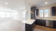 Located at Station Square 1A, this four-floor residence is designed with contemporary finishes and a thoughtful layout that flows across its multiple levels. The open-concept main living area centers around a well-equipped kitchen featuring dark espresso cabinetry, white quartz countertops, a stone tile backsplash, and a full suite of stainless steel appliances including a gas range, dishwasher, microwave, and refrigerator. A central island with pendant lighting above anchors the space, which opens seamlessly into the living area, where light wood-tone flooring and multiple windows invite natural light throughout. Bedrooms are carpeted and bright, with one featuring a striking vaulted ceiling, curved bay windows, and abundant sunlight. Another bedroom showcases a tray ceiling with crown molding detail and dual windows. Additional bedrooms are finished with neutral tones and recessed lighting. The bathrooms are cleanly designed; one includes a long quartz vanity, tile flooring, and a glass-enclosed shower, while another offers a granite-topped vanity with a shower-tub combination. A staircase connects all four floors, providing a well-structured and spacious multi-level living experience.