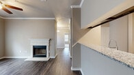 Located at 6201 SW Mallet Rd in Bentonville, Arkansas, this single-story residence offers a thoughtfully designed layout with a cohesive blend of comfort and modern finishes. The living room serves as a central gathering space, highlighted by a classic white-mantled fireplace with marble surround, crown molding, a ceiling fan, and hardwood-style flooring that extends throughout the main areas. Natural light filters in through windows fitted with blinds, contributing to a warm, inviting ambiance.

The galley-style kitchen is well-equipped, featuring dark espresso cabinetry, granite countertops, stainless steel appliances including a refrigerator, range, microwave, and dishwasher, and a stainless undermount sink. A pass-through counter connects the kitchen to the adjacent living and dining areas, enhancing the open feel of the space. Double doors at the end of the kitchen provide additional storage or pantry access.

The bedrooms are carpeted for comfort, each with a ceiling fan and natural light from exterior windows. A spacious walk-in closet offers wire shelving and a wall-mounted rack system for organized storage. The bathroom includes a granite-topped vanity with dark cabinetry, wood-style flooring, and a tiled tub-shower combination.