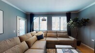 Located at 415-425 N Front St in Columbus, Ohio, this single-floor residence offers a thoughtfully designed layout that balances comfort and functionality. The living room serves as the heart of the space, featuring bold blue-gray walls, crown molding, and multiple windows fitted with blinds and curtains that allow ample natural light while maintaining privacy. The room accommodates a large sectional sofa and a modern arc floor lamp, creating an inviting atmosphere.

The kitchen features light wood cabinetry, white countertops, hardwood flooring, and stainless steel appliances including a range, over-the-range microwave, and refrigerator. The efficient galley-style layout maximizes workspace and storage.

The bedrooms offer plush carpeting and generous proportions. One bedroom includes a connecting en-suite bathroom, while additional wall details and windows contribute to a bright, restful environment.

Two bathrooms are present in the unit, each featuring dual-sink vanities with light wood cabinetry, white countertops, large mirrors, and a tub-shower combination. The clean, neutral finishes provide a calm and functional aesthetic throughout both bathrooms, complementing the overall design of the residence.