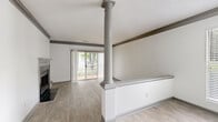 Located at 6316 Quail Hollow Rd in Charlotte, NC, this single-story home offers three bedrooms and two bathrooms within a compact, efficiently laid-out floor plan. The living area serves as a central gathering space, distinguished by a decorative column, a fireplace, and a textured ceiling. Light wood-style flooring runs throughout the main living areas, while a half-wall partition adds architectural definition to the space. A sliding glass door with vertical blinds allows natural light to filter in and provides access to an outdoor area with views of surrounding greenery.

The kitchen features rich, dark cabinetry with brushed nickel hardware, white countertops, a subway tile backsplash, and stainless steel appliances, including an electric range and built-in microwave. A window above the counter brings in additional natural light.

All three bedrooms are carpeted and bright, each receiving natural light through large windows with blinds. The primary bedroom includes direct access to a dedicated closet and an en-suite bathroom. One additional bedroom features a walk-in closet. Both bathrooms are finished with white tub-shower combinations, light wood-style flooring, and dark wood vanities with white countertops.