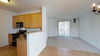 This single-floor unit at Dover Chase Apartments offers a clean, functional layout designed for comfortable living. The kitchen is equipped with stainless steel appliances, including an electric range, over-the-range microwave, and dishwasher, complemented by warm honey-toned cabinetry and granite-style countertops. Light tile flooring runs throughout the kitchen area, which opens seamlessly via a half-wall breakfast bar into the living space beyond. The living and dining areas feature neutral carpet and are bathed in natural light from a large sliding glass door fitted with vertical blinds that leads to an outdoor area. A dedicated dining space is distinguished by elegant tile flooring and a chandelier overhead. The bedrooms are carpeted and bright, with one featuring a charming bay window that fills the room with natural light and views of the surrounding neighborhood, while another offers a large picture window. The bathrooms are well-appointed with tile flooring, wood vanities with granite-style countertops, and chrome fixtures. One bathroom includes a full soaking tub with shower. An in-unit laundry closet, accessible via a bi-fold door in the kitchen area, adds everyday convenience to this thoughtfully designed residence.