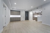 Located at 5955 Saturn St in Los Angeles, this single-floor unit showcases a clean, contemporary design throughout. The open-concept living area is bright and airy, featuring light wood-style flooring, recessed lighting, and a sleek built-in fireplace. Large black-framed windows invite abundant natural light and provide views to the outdoors. The well-appointed kitchen is equipped with wood-grain cabinetry, white quartz countertops, a decorative tile backsplash, stainless steel appliances including a gas range with hood and a french door refrigerator, and an undermount sink. The entryway features a bold dark front door alongside modern hardware and direct access to the kitchen area. Bedrooms are carpeted for comfort, with one offering sliding glass doors opening onto a private balcony. A spacious walk-in closet with built-in shelving provides ample storage. The bathrooms are elegantly finished with large-format tile, soaking tub and shower combinations enclosed by sliding glass doors in brushed gold hardware, white quartz vanities, and wood-toned cabinetry. A secondary room with built-in cabinetry offers flexible use as an office or additional storage space. The overall palette of whites, soft grays, and warm wood tones creates a cohesive, modern ambiance throughout.
