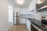 This 2-bedroom, 1-bathroom unit at 2757 Kipling Ave in Toronto's northwest end offers a clean, modern interior across a well-organized single floor. Light-toned hardwood-style flooring runs throughout, creating a bright and cohesive feel. The open living room is a standout feature, anchored by a wide floor-to-ceiling window that fills the space with natural light and frames views of the surrounding Toronto skyline. A baseboard heating unit runs beneath the windows, ensuring year-round comfort. The kitchen is thoughtfully updated with white shaker-style cabinetry, a subway tile backsplash, grey countertops, and stainless steel appliances including a refrigerator, dishwasher, range, and over-the-range microwave. The primary bedroom is generously sized, with a window for natural light and a dedicated closet. The second bedroom also features a window and easy access to the main hallway. A walk-in closet with a full-length hanging rod provides additional storage. The bathroom is finished with floor-to-ceiling white subway tile surrounding a soaker tub and shower combo with chrome fixtures. White walls and textured ceilings throughout contribute to the unit's clean, refreshed aesthetic.