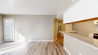 This single-floor residence offers a thoughtfully designed layout with a cohesive, modern aesthetic defined by neutral tones and quality finishes throughout. The open living area is bright and welcoming, featuring light wood-style flooring, crisp white baseboards, and an abundance of natural light streaming through multiple windows and a glass door that leads to the exterior.

The galley-style kitchen is well-equipped, showcasing white shaker cabinetry with brushed hardware, granite-look countertops, a subway tile backsplash, and stainless steel appliances including a range and refrigerator. A peninsula counter connects the kitchen to the living space, providing additional workspace and a casual dining option.

The bedrooms offer a comfortable retreat, finished with plush carpet flooring and neutral wall tones. Each room receives natural light and provides a calm, restful atmosphere. A hallway connects the private areas of the home to the shared spaces seamlessly.

The bathroom is clean and functional, featuring a white vanity with granite-style countertops, a large mirror, and a full tub-shower combination. Wood-style flooring extends into the bathroom, maintaining a consistent design language.

Overall, the space presents a clean, move-in-ready interior with a neutral palette that provides an ideal canvas for personalization.