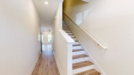 This two-story home is thoughtfully designed to maximize functionality across its layout. The ground floor serves as the main living area, featuring an open-concept kitchen equipped with white shaker cabinetry, granite countertops, a central island with a sink, stainless steel appliances, and recessed lighting — all complemented by light hardwood-style flooring. The adjacent living area is bright and airy, boasting large windows, a ceiling fan, and a rear door that invites natural light and outdoor views. A hallway connects the main spaces and leads to the attached garage, which includes an automatic door opener and a clean concrete floor. Upstairs, the more expansive second floor houses all three bedrooms, each featuring light hardwood-style flooring, neutral walls, and windows with outdoor views that fill the rooms with natural light. Each bedroom is served by a dedicated closet equipped with wire shelving systems for organized storage. The three bathrooms are consistently appointed with granite-topped white vanities, hardwood-style flooring, and tub-shower combinations. The cohesive design throughout — neutral tones, clean finishes, and consistent flooring — gives the home a fresh, move-in-ready feel.