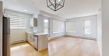 This well-designed 3-bedroom, 2-bathroom single-floor unit at 9660 229 St NW offers a clean, modern aesthetic throughout. Light hardwood flooring flows continuously across the entire space, creating a cohesive and airy feel. The open-concept living and kitchen area serves as the heart of the unit, anchored by a striking geometric pendant light fixture. The kitchen features light wood cabinetry, a subway tile backsplash, stainless steel appliances, and a functional peninsula with a sink — ideal for both everyday use and entertaining. Large windows with layered zebra blinds allow abundant natural light to fill the living area, which also benefits from direct outdoor access through two exterior doors. A central hallway connects the bedrooms and bathrooms, maintaining a logical and efficient floor plan. The three bedrooms are bright and well-proportioned, each featuring the same warm hardwood flooring, generous windows with zebra blinds, and baseboard heating. The primary bedroom offers a comfortable footprint suitable for a full bedroom suite. Both bathrooms are finished in crisp white, featuring full tub-shower combinations, modern vanities with wood cabinetry, and clean tile work. A dedicated closet provides additional storage. The overall design is contemporary, minimal, and move-in ready.