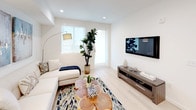Located at 8740 S La Tijera Blvd in Los Angeles, this single-floor residence showcases a clean, contemporary design with a cohesive neutral palette throughout. The open-concept kitchen is a standout feature, equipped with high-gloss white cabinetry extending to the ceiling, a marble-style quartz island with bar seating, stainless steel appliances including a refrigerator, range, microwave, and dishwasher, and under-cabinet lighting that accentuates the bright, streamlined aesthetic. Light hardwood flooring runs through the kitchen and living areas, contributing to an airy, cohesive feel.

The living room is well-proportioned, featuring recessed lighting, large windows that welcome natural light, and direct access to an exterior door, enhancing the sense of openness. The bedroom offers a comfortable retreat with plush carpet flooring, large windows fitted with roller shades for light control, and ample space for furnishings.

The bathroom is finished with large-format gray tile flooring, a white vanity with integrated sink, and a full soaking tub with a curved curtain rod. The overall ambiance of the unit is modern and inviting, with a consistent design language of white walls, clean lines, and contemporary finishes throughout.