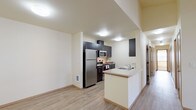 This single-floor unit offers a functional and modern layout designed for comfortable everyday living. The kitchen serves as a standout feature, showcasing dark espresso cabinetry that reaches to the ceiling, stainless steel appliances including a refrigerator, electric range, and over-the-range microwave, along with light-toned countertops and a peninsula with a built-in sink. Light wood-style flooring runs through the kitchen and adjacent living area, creating a clean, cohesive aesthetic. The open living space benefits from natural light and provides a versatile area for relaxing or entertaining. Multiple bedrooms are finished with plush carpet flooring, baseboard heaters, and windows fitted with blinds that offer views of surrounding greenery. The rooms are well-proportioned and provide a calm, neutral atmosphere. The unit includes two bathrooms: a full bath featuring a soaking tub and shower combination, dark vanity cabinetry, a wide mirror, and tile flooring, as well as a half bath with a similar vanity design and stone-look tile. The entry area transitions smoothly between carpeted and wood-style flooring, adding a welcoming feel. Throughout, the warm cream-toned walls and consistent finishes contribute to a cohesive, move-in-ready environment.