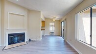 Located at 2130 S Santa Fe Ave in Vista, CA, this 2-bedroom, 1-bathroom home offers a well-organized, comfortable layout with consistent light wood-style flooring and warm neutral tones throughout. The open living room is a standout space, featuring a ceiling fan, a wood-burning fireplace with a classic white surround, and a sliding glass door that opens to a private balcony with scenic views of the surrounding hills and neighborhood. Large windows flood the room with natural light and frame pleasant outdoor vistas. Adjacent to the living area, the galley-style kitchen is efficiently designed with warm wood cabinetry, dark granite-style countertops, and white appliances including a gas range, refrigerator, and dishwasher. A utility area off the living room conveniently houses an in-unit washer and dryer. Both bedrooms are bright and well-proportioned, each with windows that bring in natural light and views of the greenery outside. The primary bedroom includes access to two closets, one of which is a dedicated walk-in with built-in shelving and hanging rods. The bathroom features a wide vanity with light wood cabinetry, a large mirror, and a separate shower area. Textured ceilings are present throughout the home.
