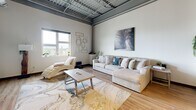Located at 324 W Water St in downtown Syracuse, NY, this two-bedroom, two-bathroom urban loft showcases a striking industrial-modern design across a single, well-organized floor. Soaring ceilings with exposed steel beams and silver ductwork define the open-concept living and kitchen area, creating a spacious, airy atmosphere complemented by warm hardwood-style flooring throughout.

The kitchen features rich, dark-wood cabinetry paired with black granite countertops and a full suite of stainless steel appliances, including a range, microwave, dishwasher, and refrigerator. A breakfast bar provides additional seating and connects seamlessly to the living area, which benefits from natural light through large windows with outdoor views.

The primary bedroom is generously proportioned, offering ample space for comfortable living. The second bedroom is bright and windowed, with multiple natural light sources. Both bedrooms are accessed via a hallway with dark-finish doors that maintain the space's cohesive aesthetic.

The primary bathroom features a wide double-vanity with dark cabinetry, dark granite countertops, a large mirror, and light tile flooring. The second bathroom is clean and functional with light tile floors and a tub-shower combination. A hallway entry with wood flooring completes the layout, tying together this well-appointed urban residence.