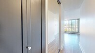 Located on the fifth floor at 1 Chapel St in Nanaimo, BC, this one-bedroom, one-bathroom unit offers a thoughtfully designed layout with a bright, open feel throughout. Light-toned hardwood flooring runs continuously across the living, bedroom, and hallway areas, creating a cohesive and clean aesthetic.

The living room is a standout space, featuring expansive floor-to-ceiling sliding glass windows that frame sweeping views of the surrounding cityscape and mountain backdrop. Abundant natural light fills the room throughout the day, and a private balcony provides direct access to the outdoors. Baseboard heating is integrated along the window walls. The adjacent kitchen is compact and functional, featuring white cabinetry, overhead track lighting, and a clean, efficient layout.

The generously sized primary bedroom also benefits from large windows offering the same impressive mountain and city views, filling the room with natural light. A built-in mirrored sliding-door closet provides practical storage, while a bold dark-paneled interior door adds a touch of contrast to the otherwise light and neutral palette.

The bathroom is finished with white subway tile from floor to ceiling, a soaker tub with an adjustable overhead shower, and clean white fixtures throughout, conveying a simple and polished look. The overall ambiance of the unit is bright, airy, and functional — well-suited for comfortable urban living in Nanaimo.