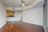 Located in the heart of Orlando at 111 East Washington Street, this well-appointed 3-bedroom, 2-bathroom residence offers a thoughtfully designed open-concept layout across a single floor. The living, dining, and kitchen areas flow seamlessly together, anchored by rich hardwood-style flooring and a ceiling fan that enhances the bright, airy atmosphere. The modern kitchen is a standout feature, boasting sleek white cabinetry, dark granite countertops, a tiled mosaic backsplash, stainless steel appliances, and a large center island with elegant pendant lighting overhead — ideal for both cooking and entertaining. The bathrooms echo the same contemporary aesthetic, featuring dark granite vanity tops, light-toned cabinetry, and clean tile flooring. Each of the three bedrooms offers plush carpeting and generous closet space with built-in wire shelving systems. A dedicated laundry area houses a stacked washer and dryer unit for added convenience. The residence also includes a balcony, providing an outdoor retreat. Neutral tones throughout create a clean, modern canvas, while the prime downtown Orlando location places residents steps away from city amenities, dining, and entertainment.