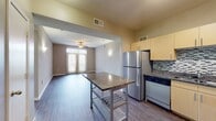 This contemporary apartment at Legacy Village offers a well-designed 920 square foot living space. The unit boasts two bedrooms, including a spacious 150 square foot primary bedroom, and two full bathrooms. The open floor plan creates a sense of spaciousness and flow throughout the apartment.

The kitchen is a standout feature, equipped with stainless steel appliances, ample cabinetry, and a large granite-topped island that doubles as a breakfast bar. The backsplash adds a touch of modern flair with its sleek tile design.

Both bathrooms are thoughtfully designed with modern fixtures, including a combination tub and shower with decorative tile accents. The vanities feature granite countertops and ample storage space.

Throughout the apartment, rich wood-look flooring adds warmth and elegance. Large windows in the bedrooms and living areas flood the space with natural light, while vertical blinds offer privacy control. Ceiling fans in the bedrooms and living room provide additional comfort.

The bedrooms are generously sized, with the primary bedroom featuring a walk-in closet. The apartment also includes additional closet space for storage needs.

Overall, this apartment combines modern aesthetics with practical living spaces, creating an inviting and comfortable home environment.