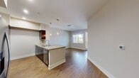 This contemporary 600 square foot apartment in Mission Viejo offers a thoughtful blend of style and functionality. The single-level layout maximizes space efficiency, featuring one bedroom and one bathroom. The heart of the home is an open-concept living area that seamlessly integrates the kitchen and living room. The kitchen boasts modern amenities, including stainless steel appliances, dark wood cabinetry, and a striking granite countertop with a curved island for casual dining or food preparation. Pendant lighting adds a touch of elegance above the island. The living space is bathed in natural light from large windows, while wood-look flooring throughout creates a warm, cohesive feel. The bedroom, measuring 140 square feet, offers plush carpeting and a spacious closet. The bathroom features a combination tub/shower, a granite-topped vanity, and large-format tile flooring. Additional amenities include recessed lighting, a separate laundry area, and a private balcony accessible from the living room, offering outdoor living space and views of the surrounding community.